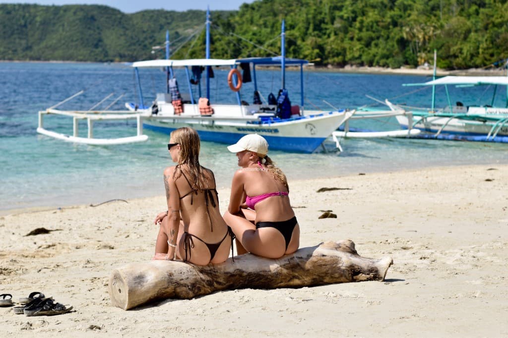 Traditional outrigger boat on a white sand beach in Port Barton