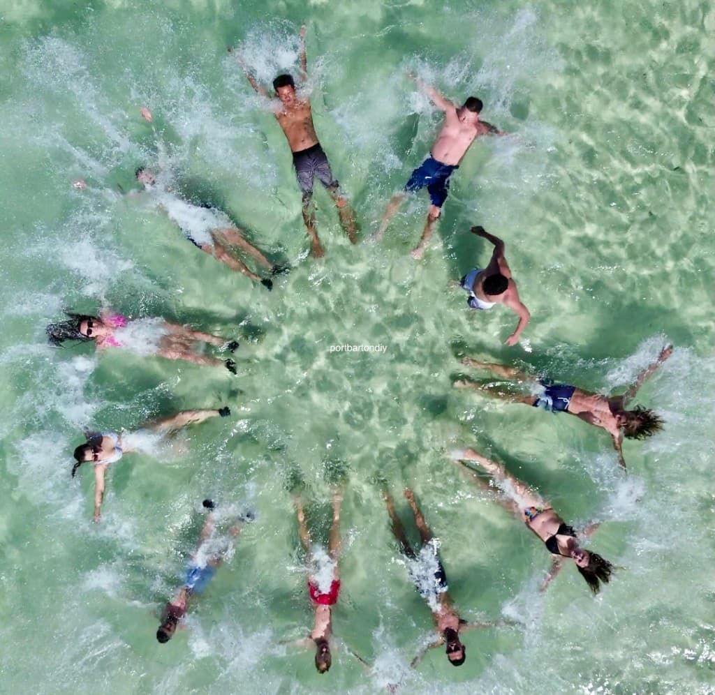 Group of travellers splashing together in shallow turquoise water