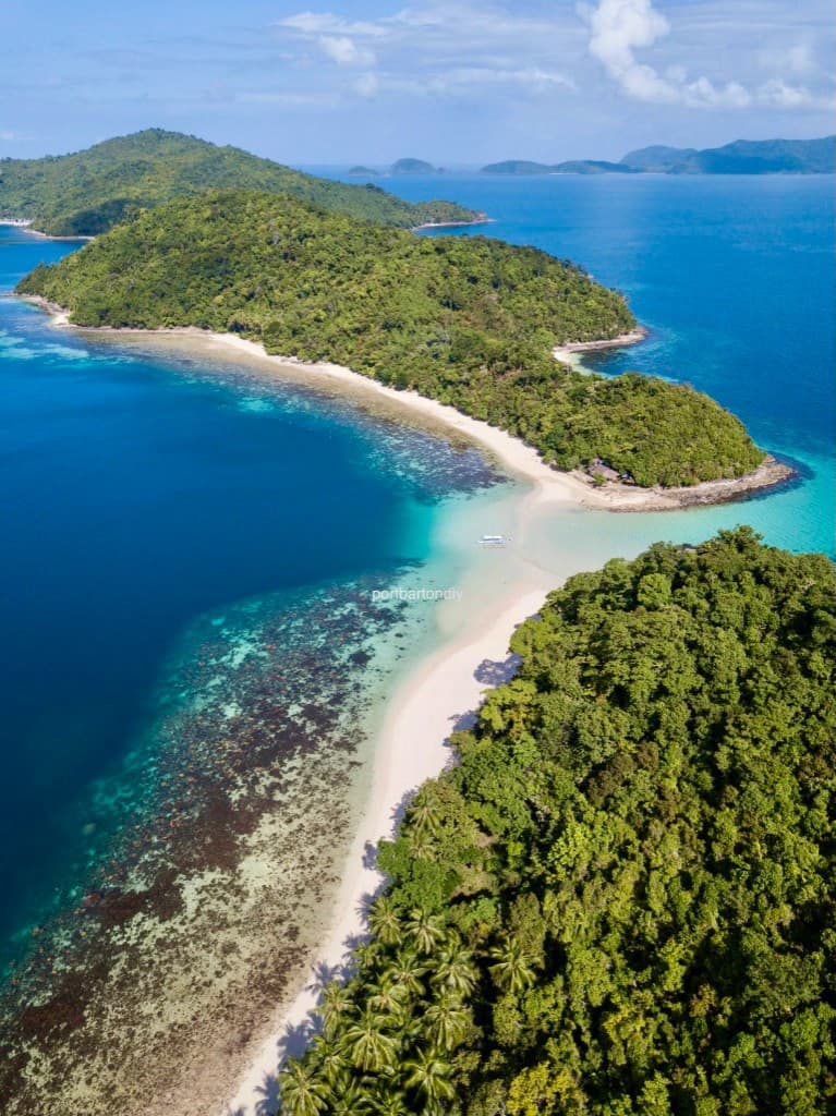 Aerial view of a sandbar connecting two lush green islands